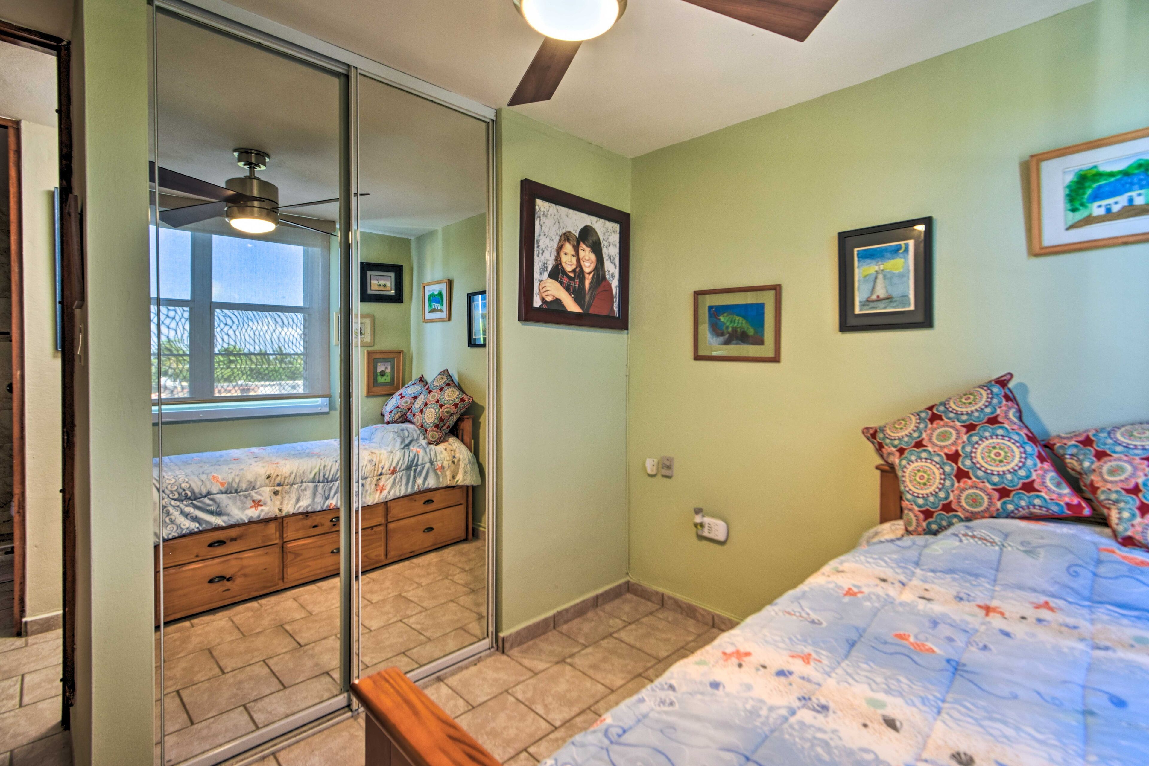 A bedroom with a bed, a dresser, a mirror, and a ceiling fan.