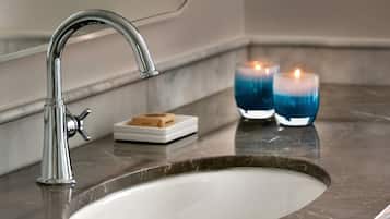 A modern bathroom with a sleek chrome faucet, a white sink, and two blue candles on the countertop.