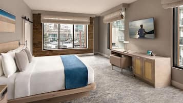 A modern hotel room with a large bed, a desk, and a view of the cityscape.