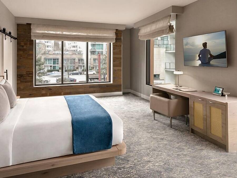Una camera d'albergo moderna con un letto grande, una scrivania e vista sulla città.