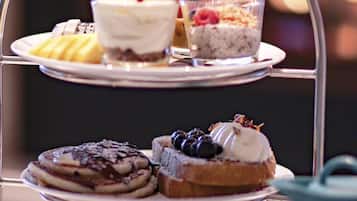 A three-tiered dessert stand with various pastries and a teapot.