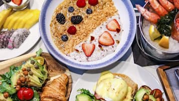 Diverses plats de petit esmorzar, com ara ous, fruita i pastissos, sobre una taula.