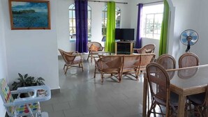 A living room with wicker furniture, a television, and a fan. - Lapiroguevilla (Grand-Baie)