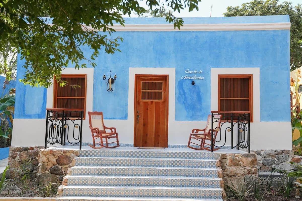 A building with a blue facade, a wooden door, and two windows.
