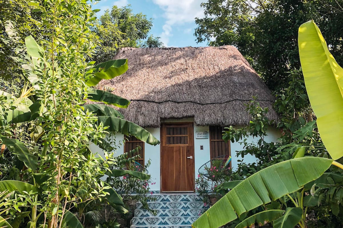 A thatched-roof house with a wooden door and a sign reading "Lodge Zulu."