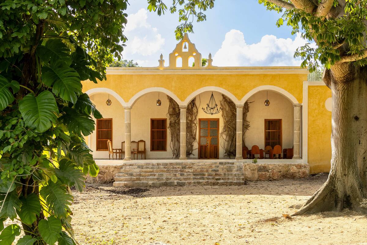 A building with a yellow facade, arched doorways, and a bell tower.