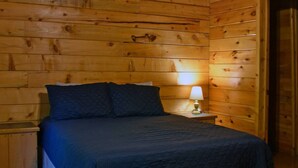 Een houten kamer met een bed, een nachtkastje en een lamp.