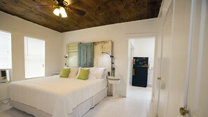 A bedroom with a large bed, a bedside table, a ceiling fan, and a door leading to another room. - Downtown Historic Neighborhood, great location. (San Antonio)
