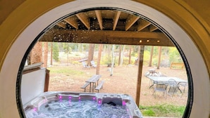 A hot tub with a circular window view of an outdoor patio area with tables and chairs. - Riverside Home w/Private Hot Tub, Fire Pit & Deck! (Keystone)