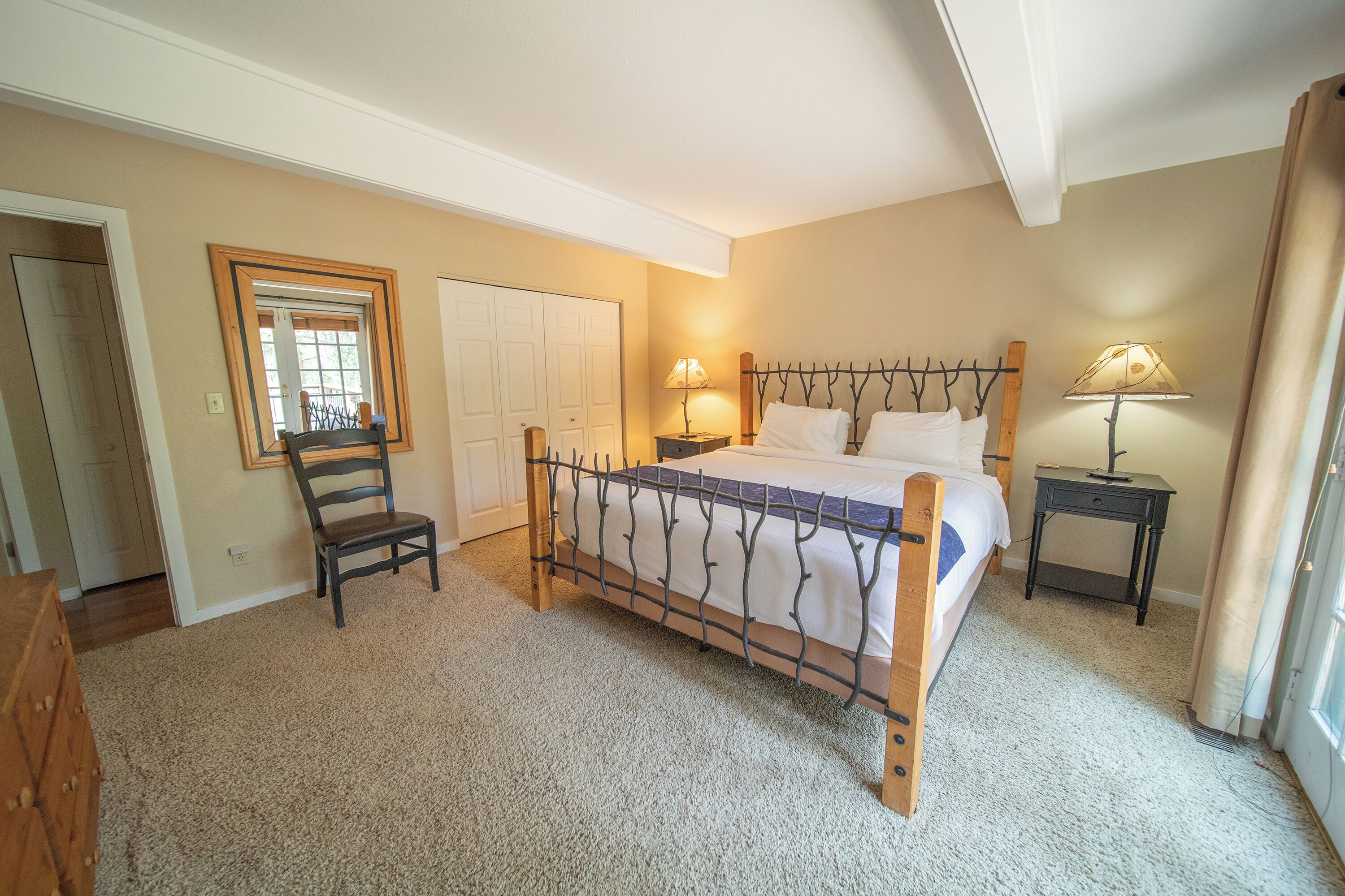A bedroom with a bed, two bedside tables with lamps, a chair, and a wardrobe.