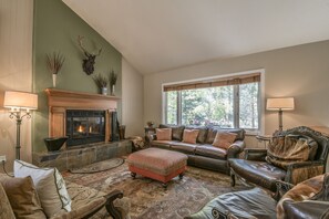 Una sala de estar acogedora con chimenea, muebles de cuero y un ventanal grande.