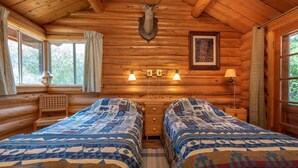A log cabin bedroom with two beds, a mounted deer head, and a framed picture on the wall. - Beautiful lakeside retreat - Perfect for the adventuresome family -pet friendly (Dubois)