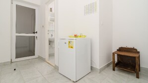 Una cocina compacta con un refrigerador blanco, una mesa de madera pequeña y una puerta que da a un baño.
