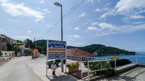 Un cartel anuncia apartamentos con vistas al mar y un paisaje montañoso de fondo.