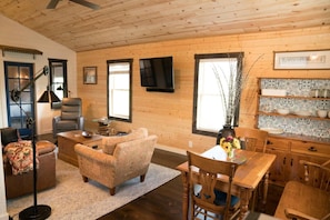 Cozy living room with a sofa, dining table, and television, offering a view of the outdoors.