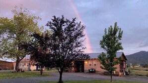 A house with a driveway, a tree in the front yard, and a rainbow in the background. - Charming well appointed Cottage in Ashland ( 800 + sq. ft. ) (Ashland)