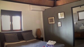 A bedroom with a sloped ceiling, a bed with pillows, a window, and a mirror. - A romantic stay and enjoy the nature! Aruba, Santa Cruz. (Santa Cruz)