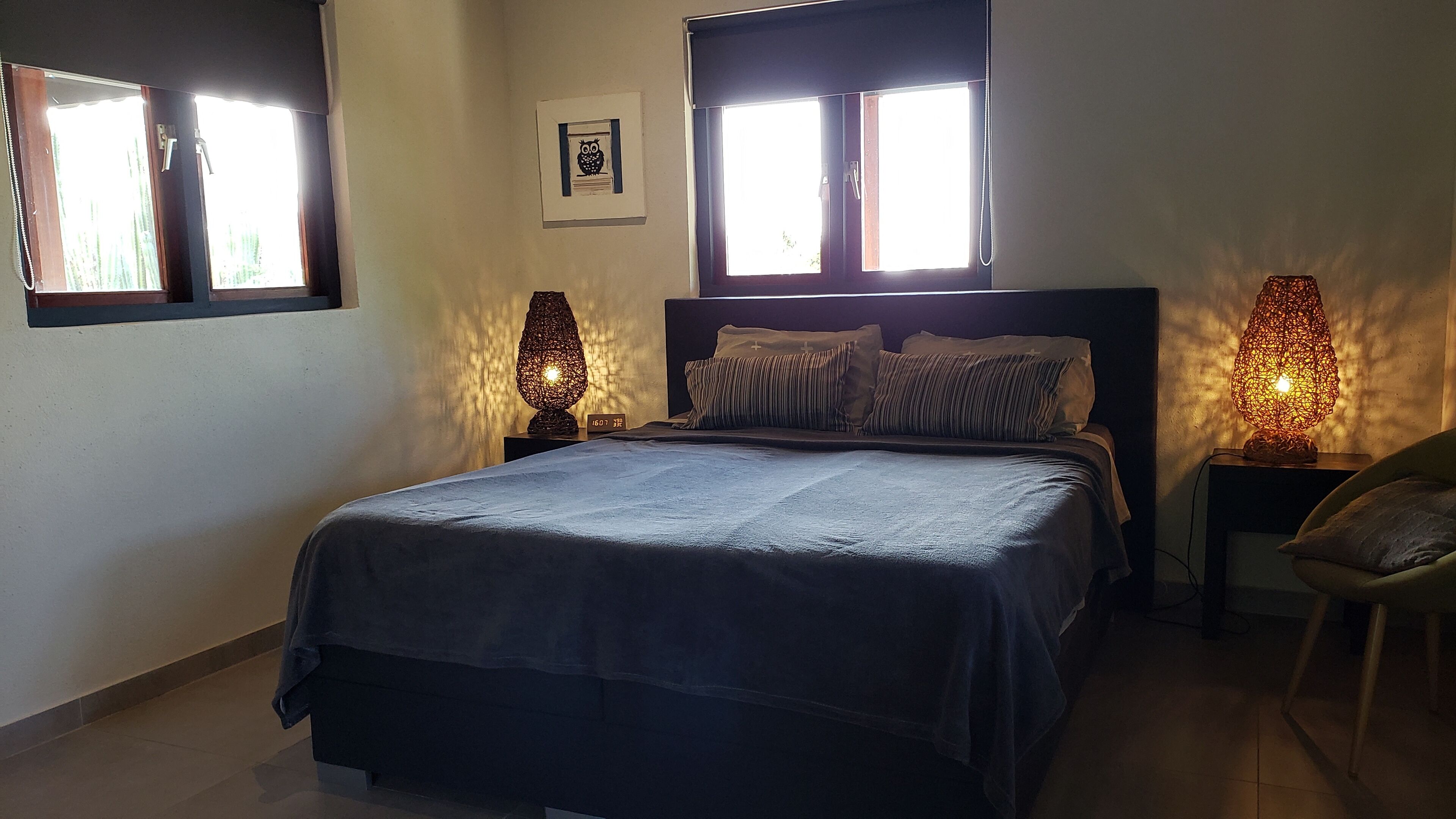 Un dormitorio con una cama, dos lámparas de noche, una ventana y un reloj de pared.