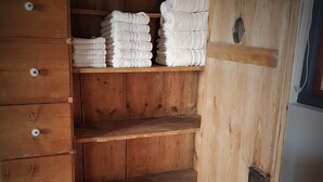 A wooden wardrobe with multiple shelves and drawers, some containing folded towels. - A romantic stay and enjoy the nature! Aruba, Santa Cruz. (Santa Cruz)