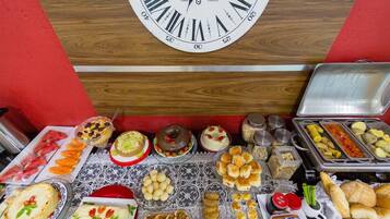 A buffet table with various food items and a clock above it.