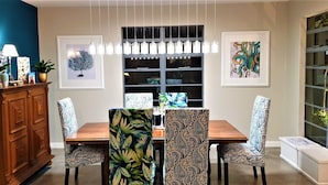 A dining area with a wooden table, patterned chairs, a cabinet, and artwork on the walls. - Hadeda Hall (Johannesburg)