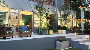 An outdoor seating area with wicker furniture, potted plants, and a small fountain. - Hadeda Hall (Johannesburg)