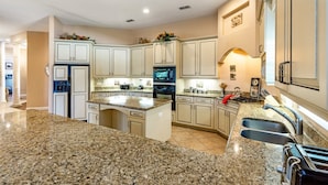 A spacious kitchen with granite countertops, a built-in oven, and a large island with a sink. - Stunning Large 7 bed Home With Private Pool, Spa, Balcony, Cinema Room, Fitness Suite and Able to see the Disney Fireworks - 467 (Kissimmee)