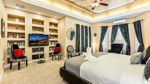 A spacious bedroom with a large bed, a television, a bookshelf, and a ceiling fan. - Stunning Large 7 bed Home With Private Pool, Spa, Balcony, Cinema Room, Fitness Suite and Able to see the Disney Fireworks - 467 (Kissimmee)
