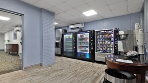 Ein sauberer, moderner Arbeitsraum mit Automaten, einer Kaffeemaschine und einem Mülleimer.
