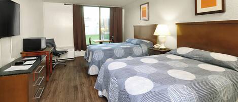 A hotel room with two beds, a desk, a chair, a TV, and a window with curtains.