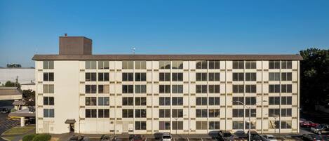 A multi-story building with a parking lot in front.
