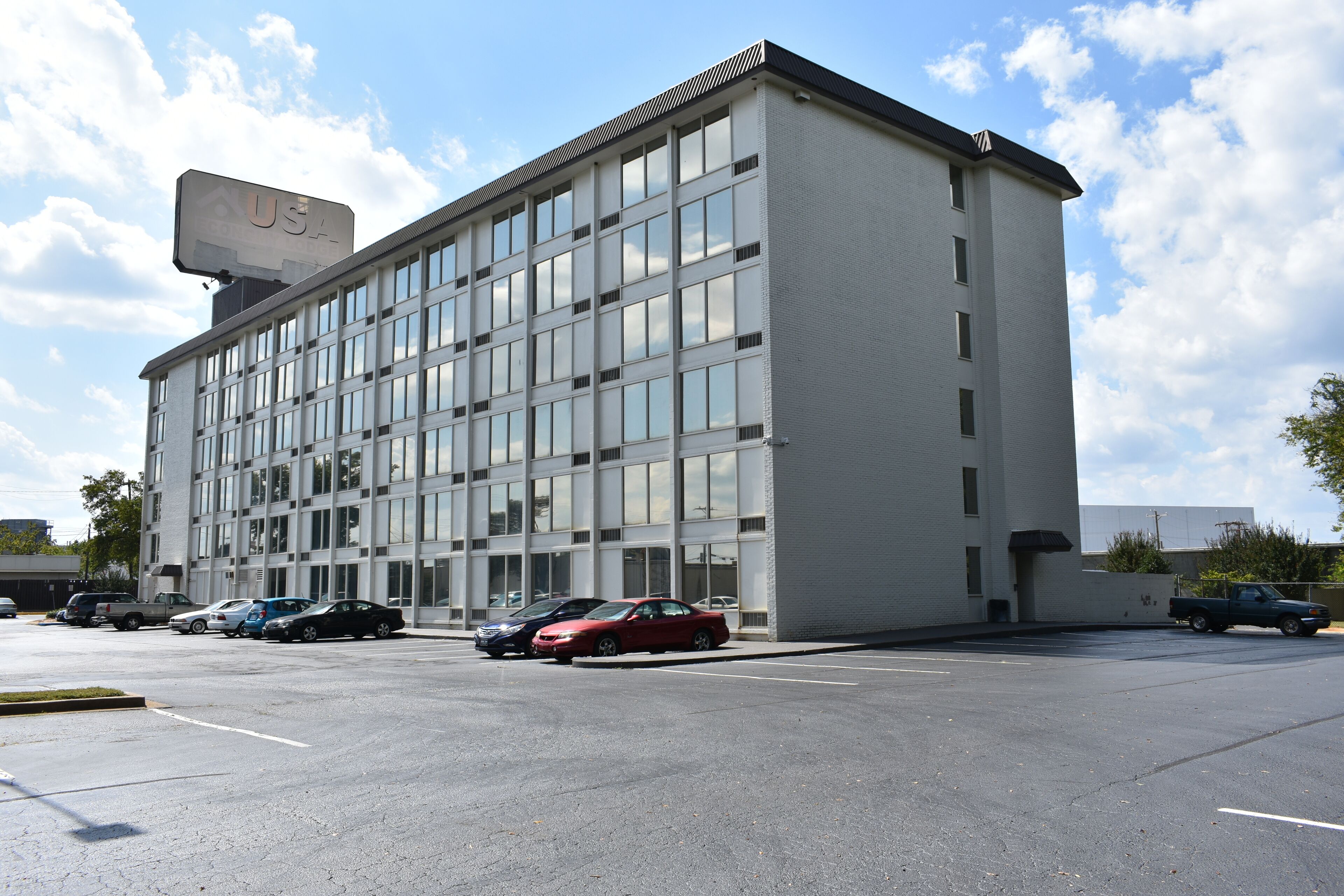 Un bâtiment moderne, orné d’un panneau indiquant « USA », avec un parking et plusieurs voitures stationnées.