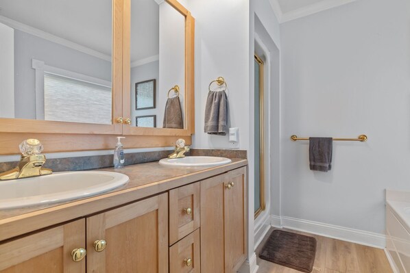 A bathroom with two sinks, a large mirror, wooden cabinets, and a towel rack.