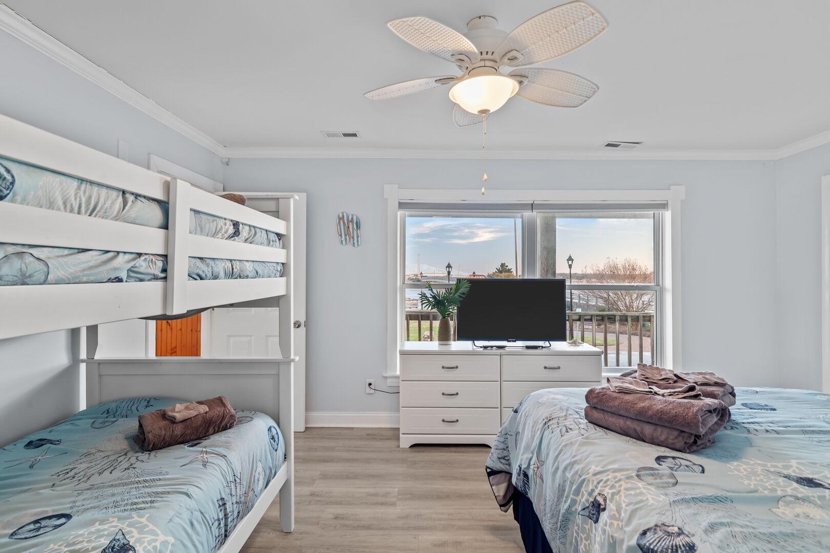 Une chambre avec des lits superposés, une télévision, une commode et une fenêtre donnant sur un paysage agréable.
