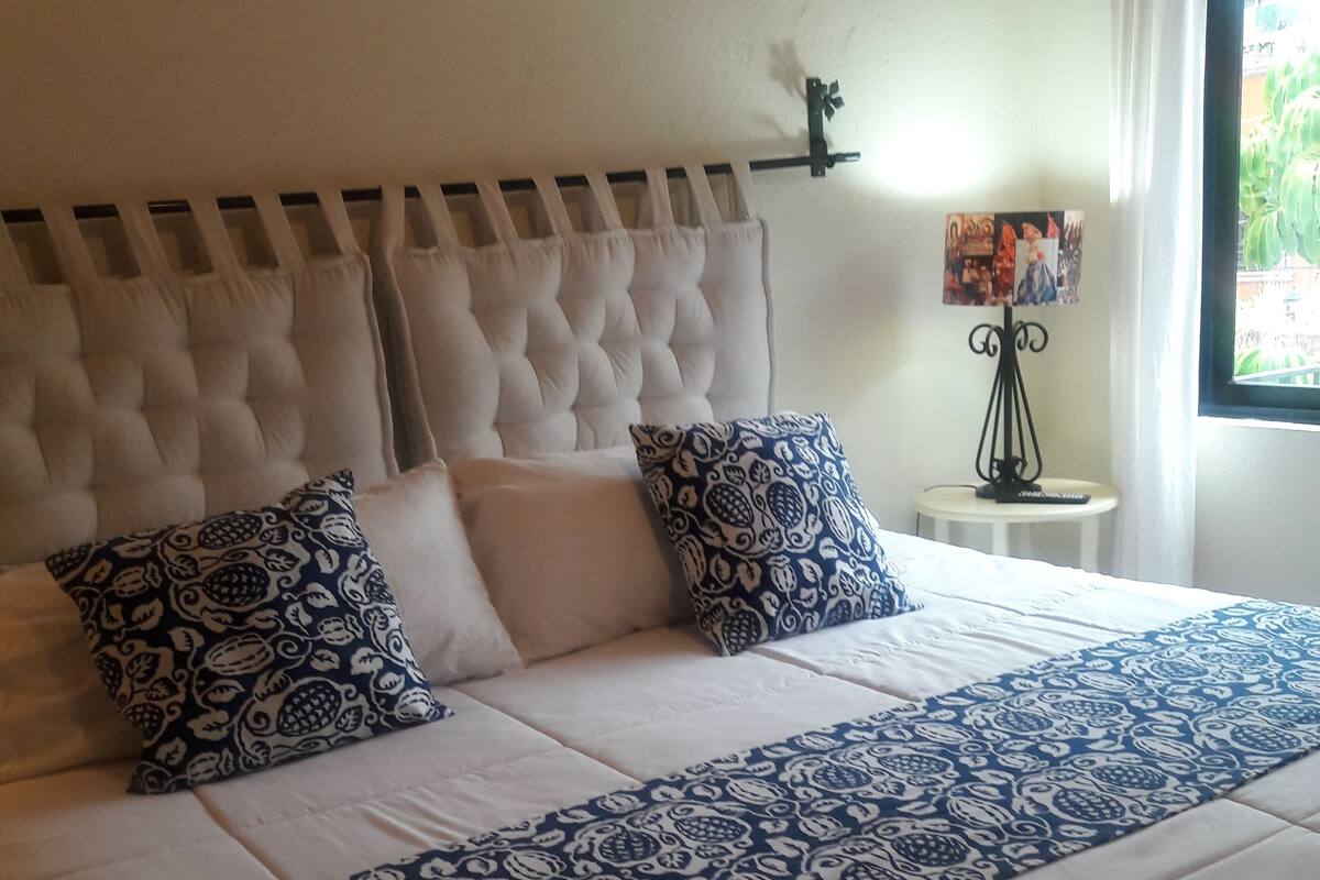 Un lit bien fait, avec une couvre-lit à motifs et deux coussins décoratifs.