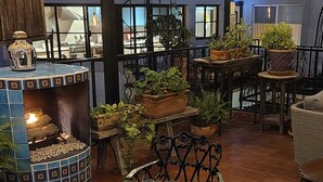 Un rincón interior acogedor con una mesa de cerámica decorativa, sillas cómodas y plantas en macetas.