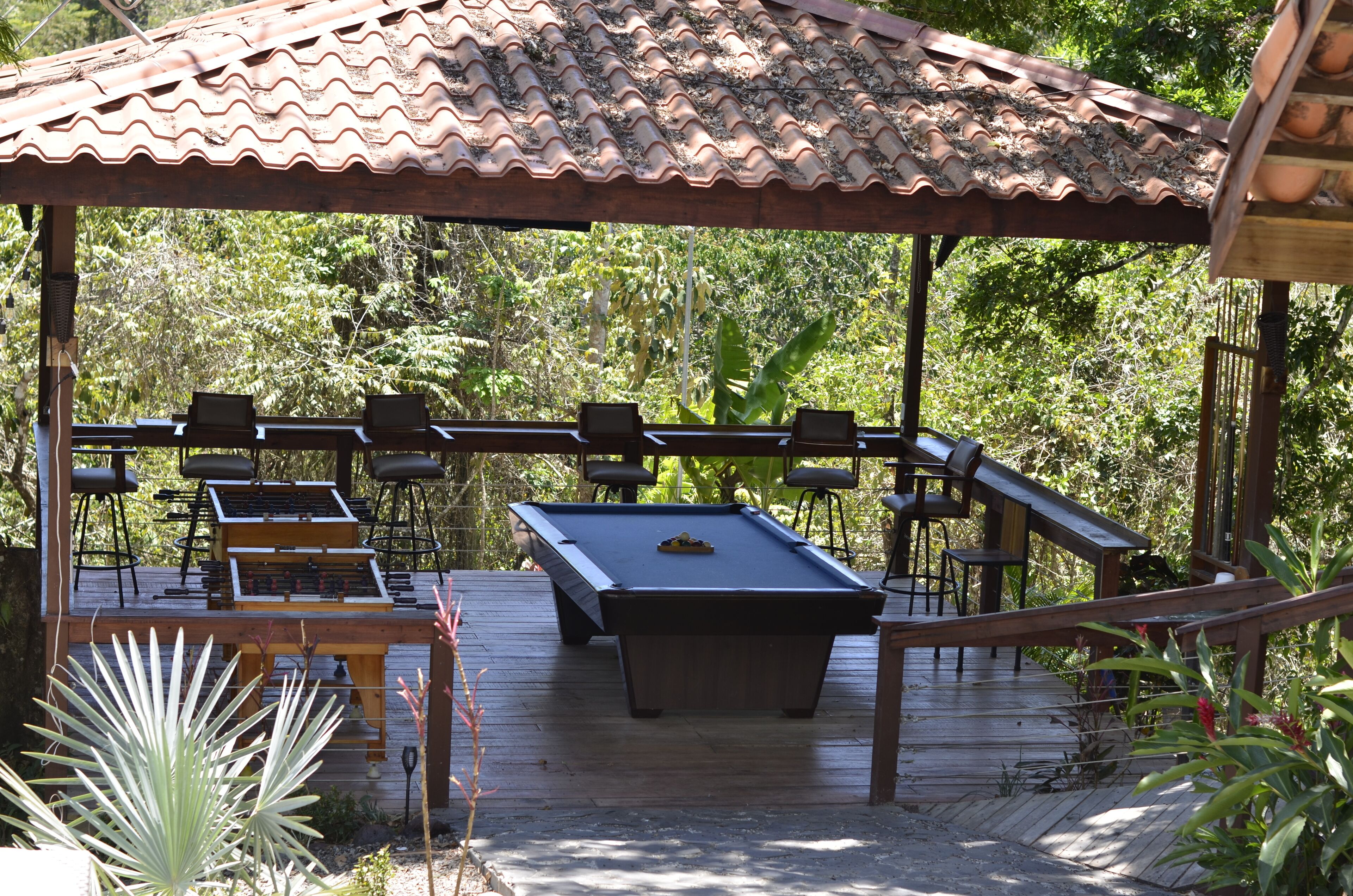 An outdoor pool area with a wooden deck, pool table, and seating.