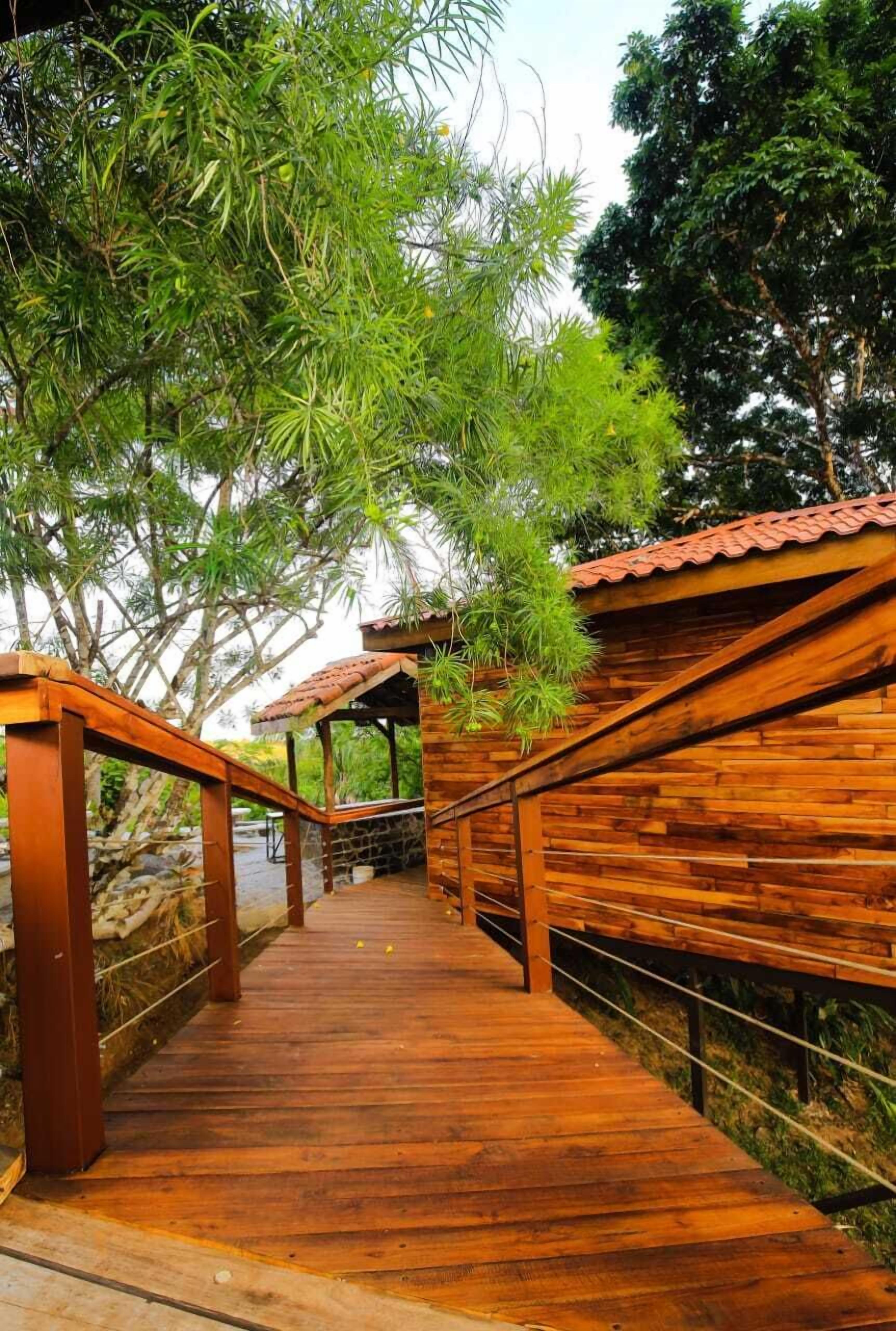 A wooden bridge with railings leading to a covered wooden structure.