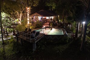 Ein Poolbereich mit Holzterrasse, umgeben von tropischer Vegetation.