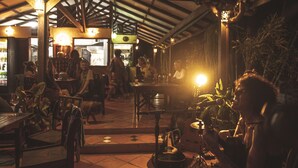 An indoor dining area with wooden tables and chairs, a tiled floor, and a high ceiling with exposed beams. - Hotel Nature Lodge Finca los Caballos (Cóbano)