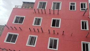 Un edificio de varios pisos con fachada rosa, múltiples ventanas y barandilla decorativa de metal en el techo.