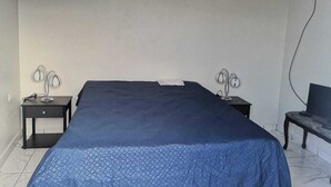 Un dormitorio con una cama grande, dos mesitas de noche y una silla.