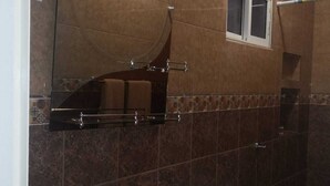 Un baño con un lavamanos blanco, un inodoro y un espejo grande sobre el lavamanos.