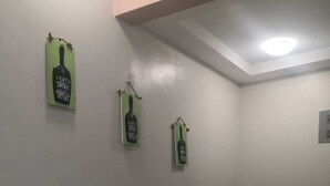 Una habitación con una silla, una mesita y tres letreros colgados en la pared.