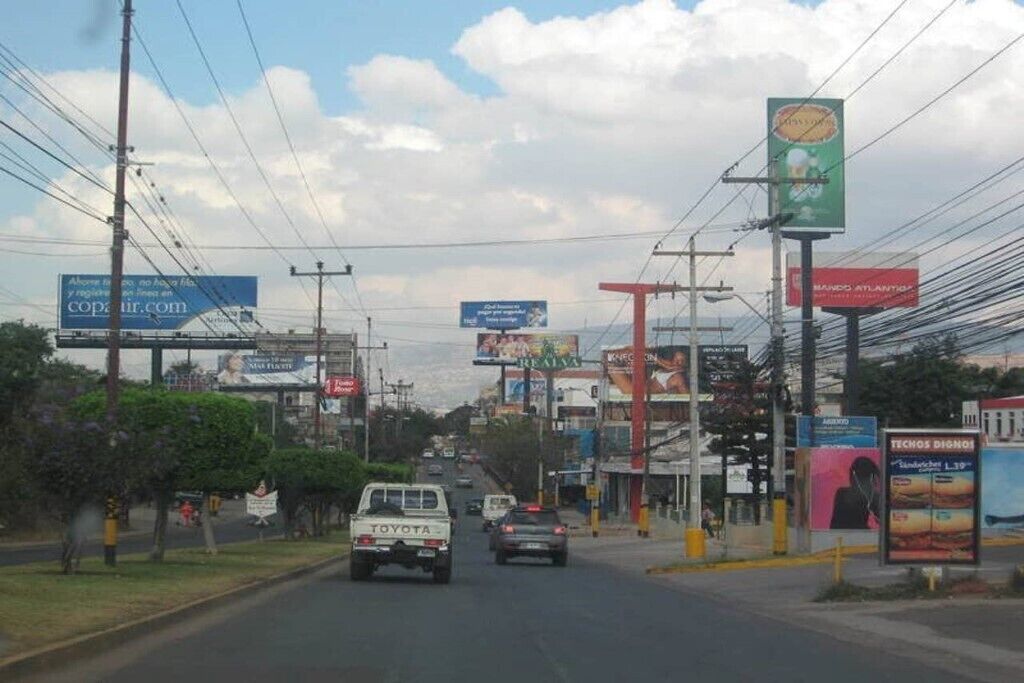 Una calle con varios carteles y anuncios, incluyendo uno destacado para 'Manu Atlantico'.