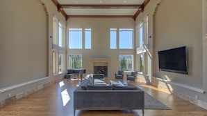 A spacious living room with a fireplace, large windows, a piano, and a flat-screen TV. - Contemporary Villa in the Napa Valley (Napa)