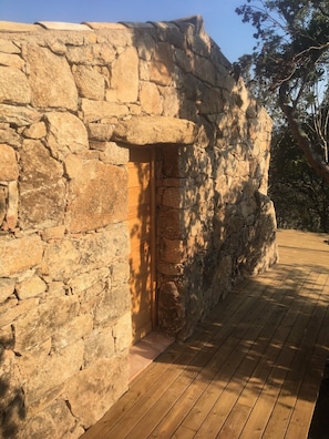 A stone building with a wooden door and a wooden deck. - AUTHENTIC BERGERIE (SOTTA)