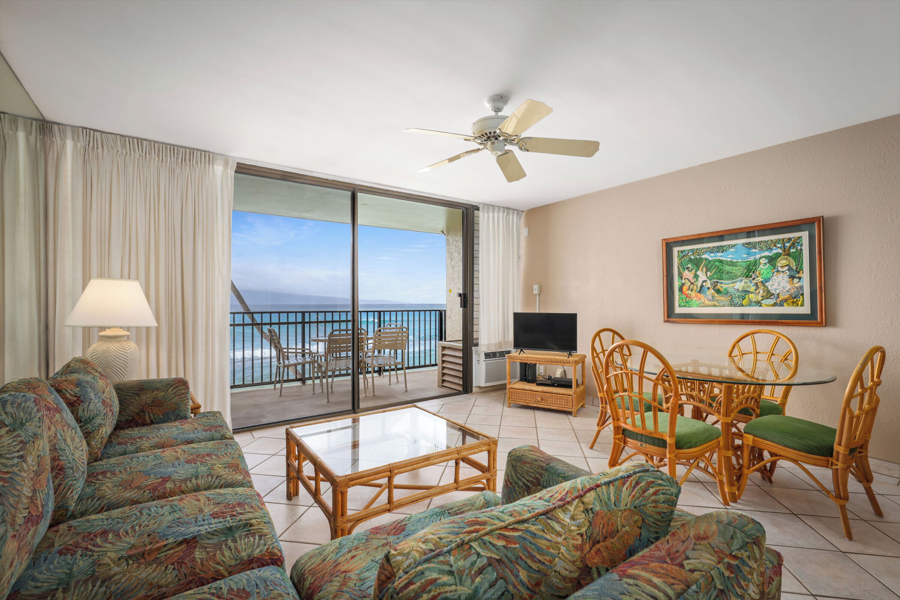 A room with a balcony, a television, wicker furniture, and a painting.