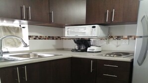A compact kitchen with dark brown cabinets, a white microwave, a coffee maker, and a sink. - 2 single rooms, and 1 double room with their private bathroom, kitchen.microwave (QUERETARO)