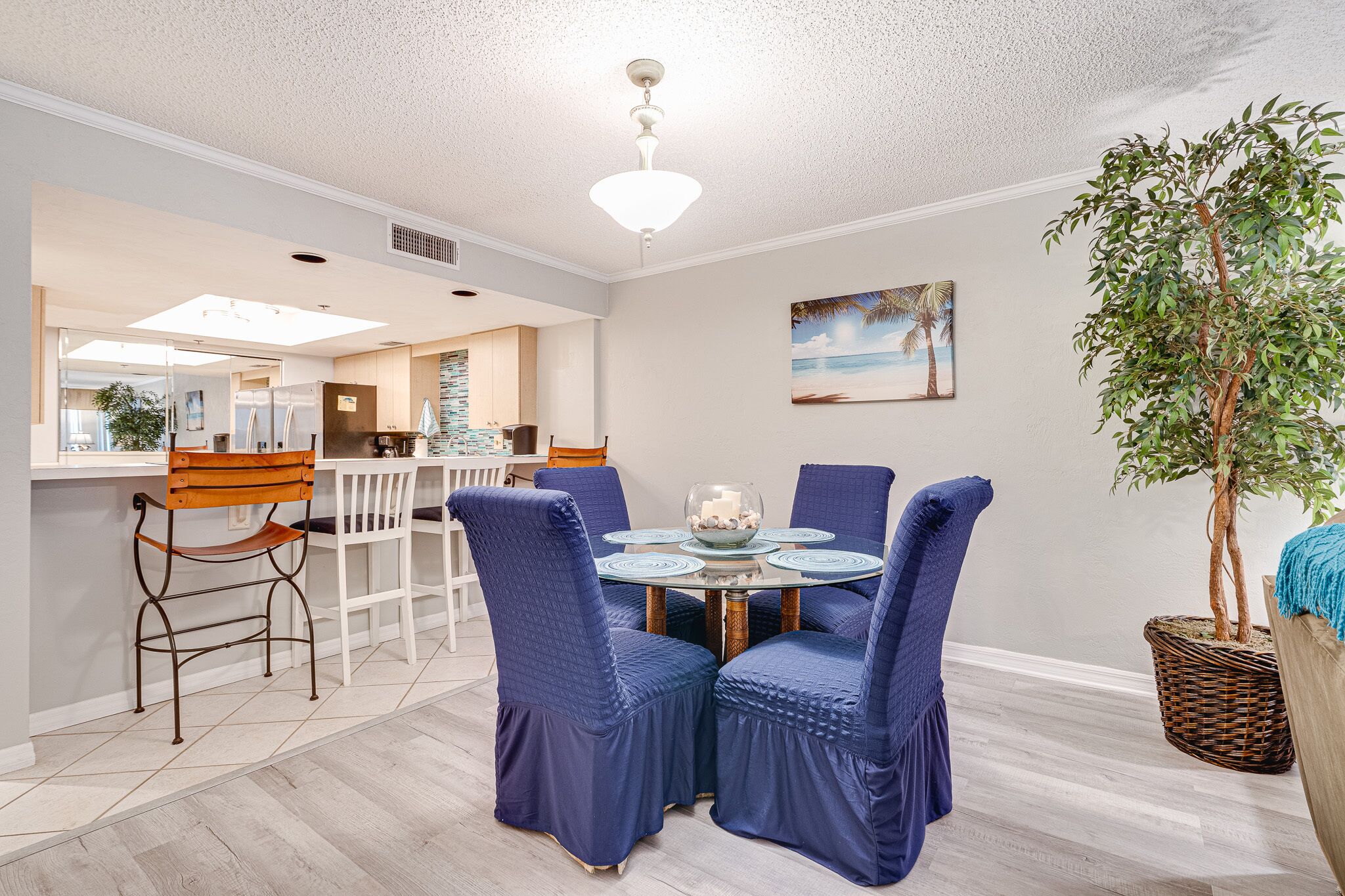 A dining area with a round table, blue upholstered chairs, and a decorative bowl centerpiece.
